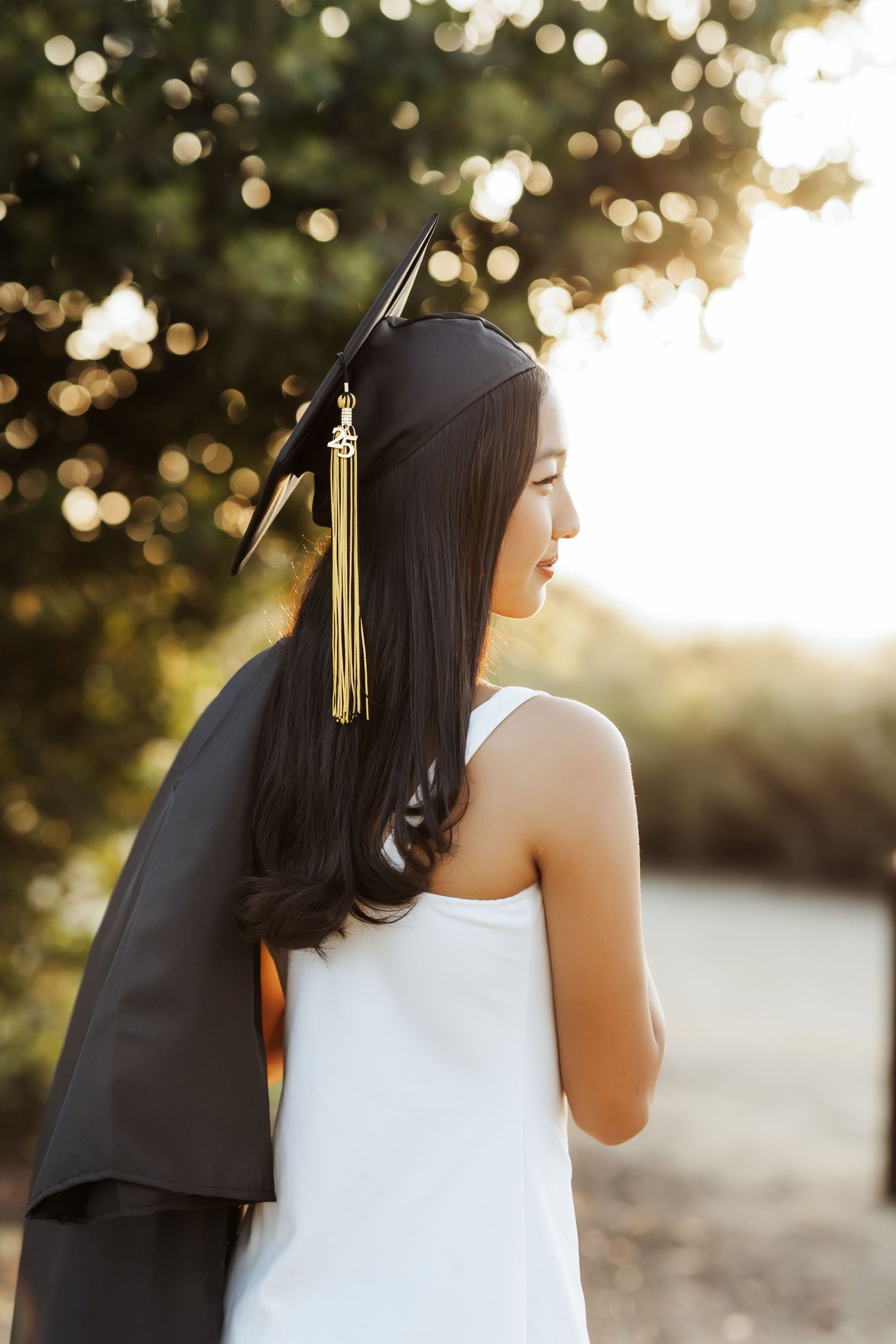 Senior portrait holding her gown wearing her cap during a sunset session in Orange County
