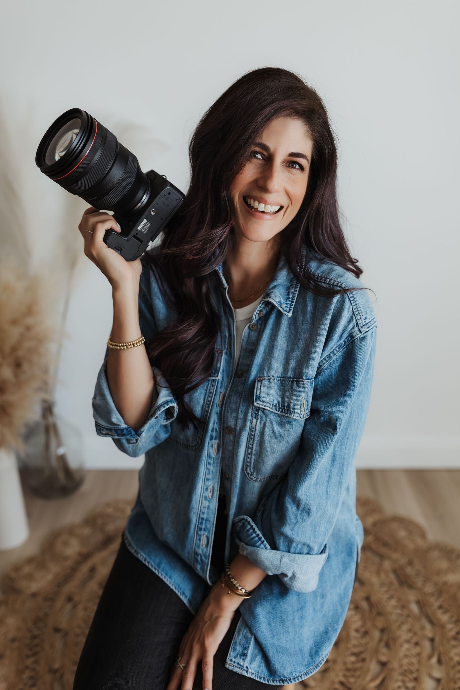Casual indoor portrait of an Orange County photographer holding a camera
