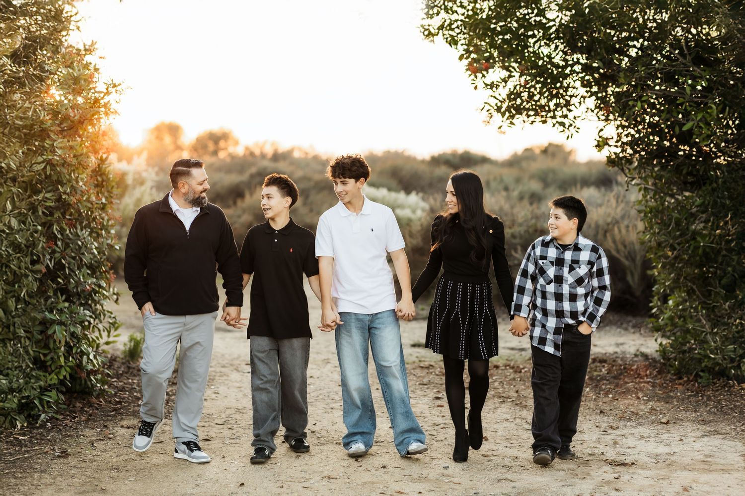 Sunset Family photo session in Orange County with family walking along a trail and looking at each other.