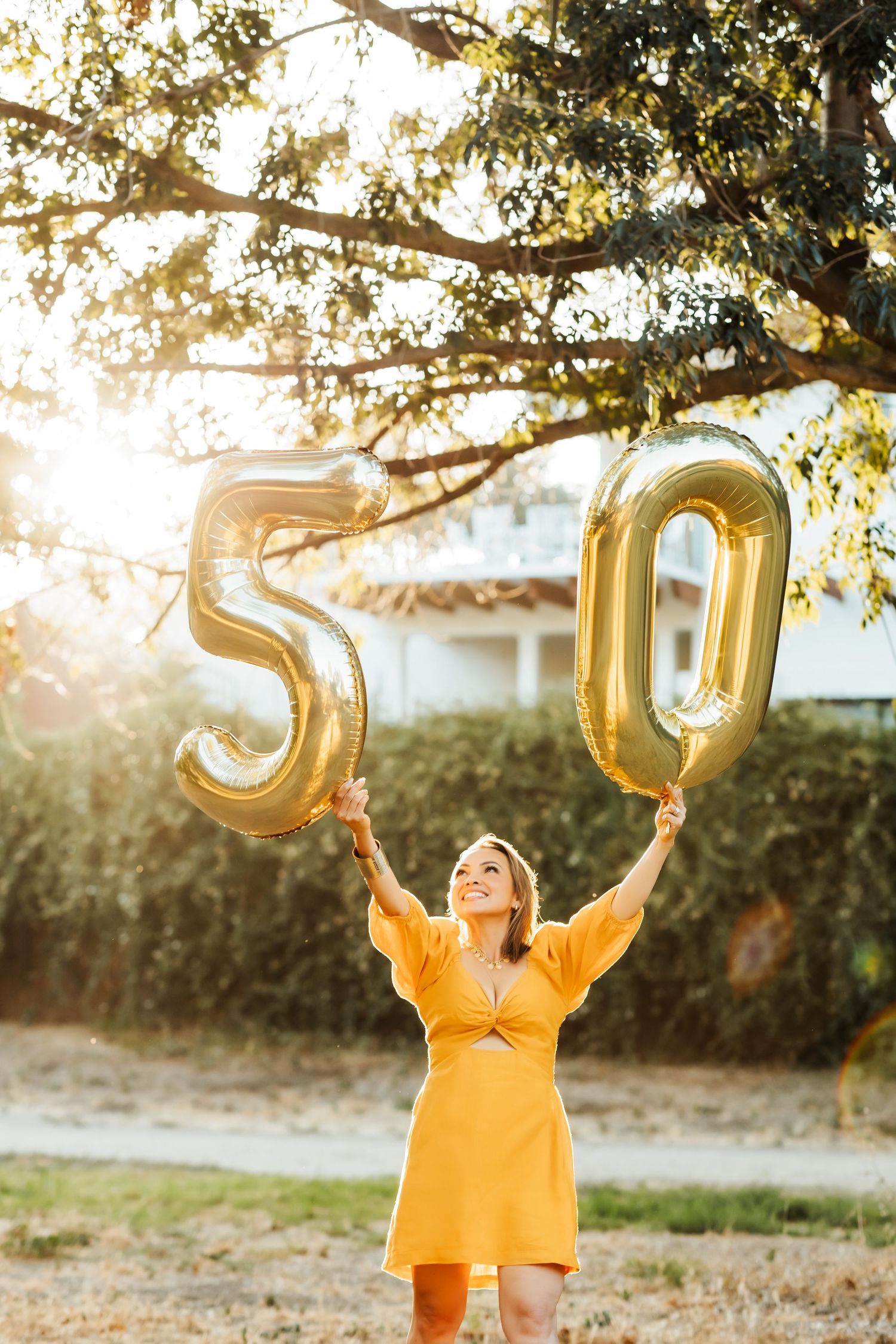 A woman celebrating her birthday holding up balloons during a sunset portrait session in Orange County