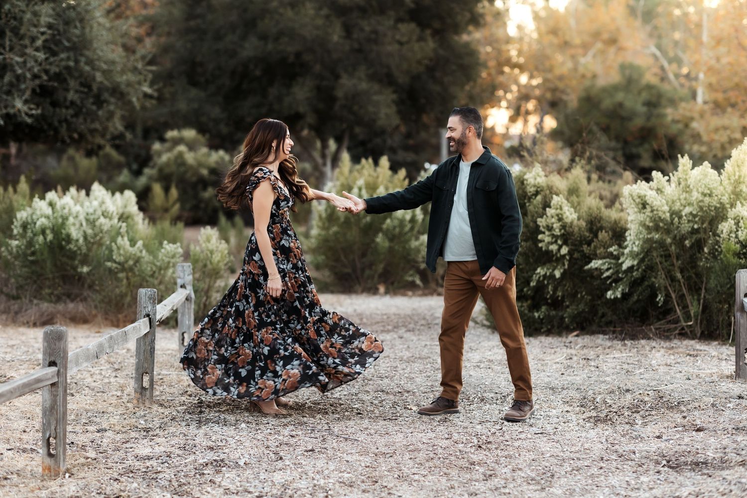 Couple dances as the husband twirls his wife during a relaxed family portrait session in Orange County