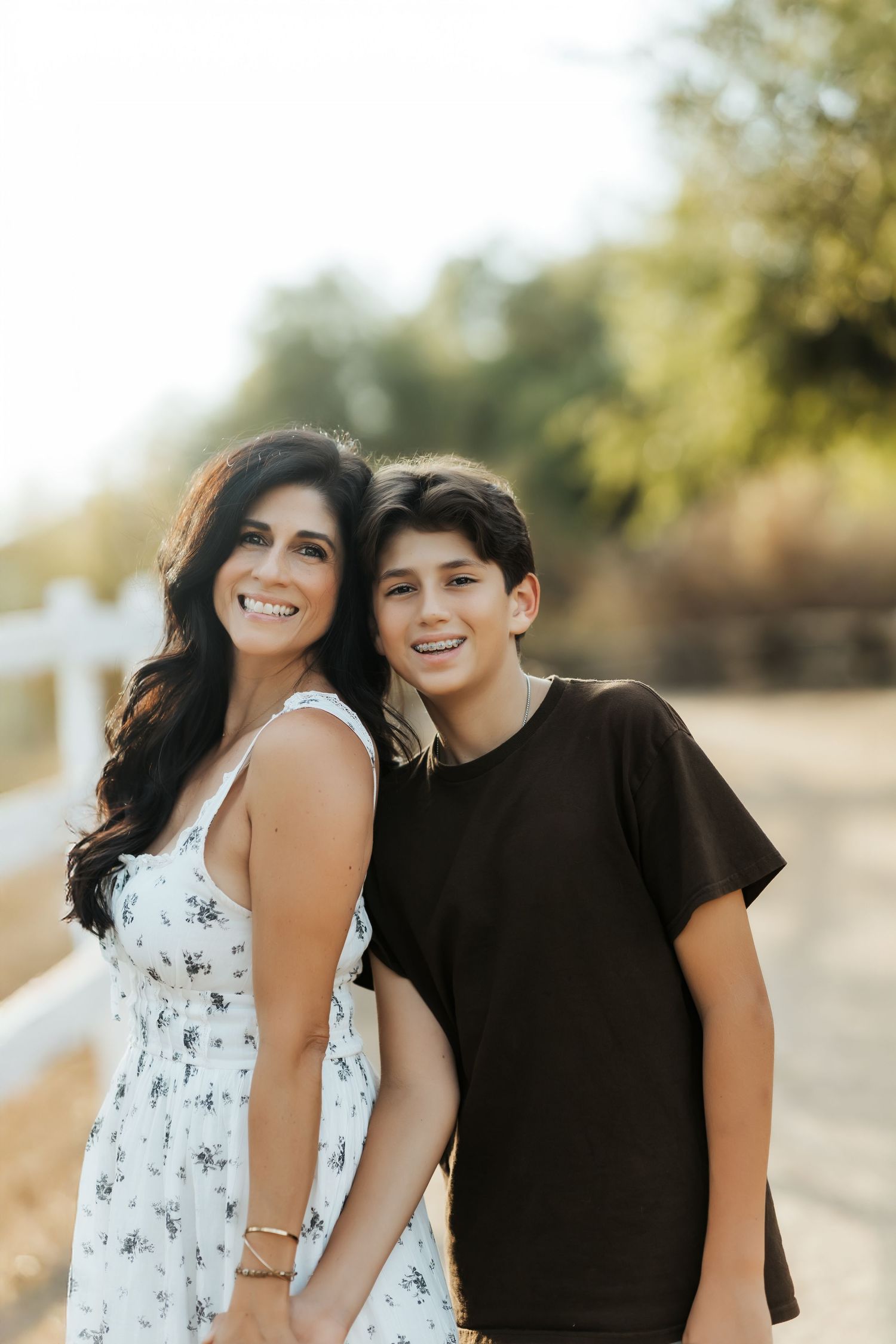 Orange County photographer holding hands with her son outdoors, standing close and sharing a sweet, candid moment.