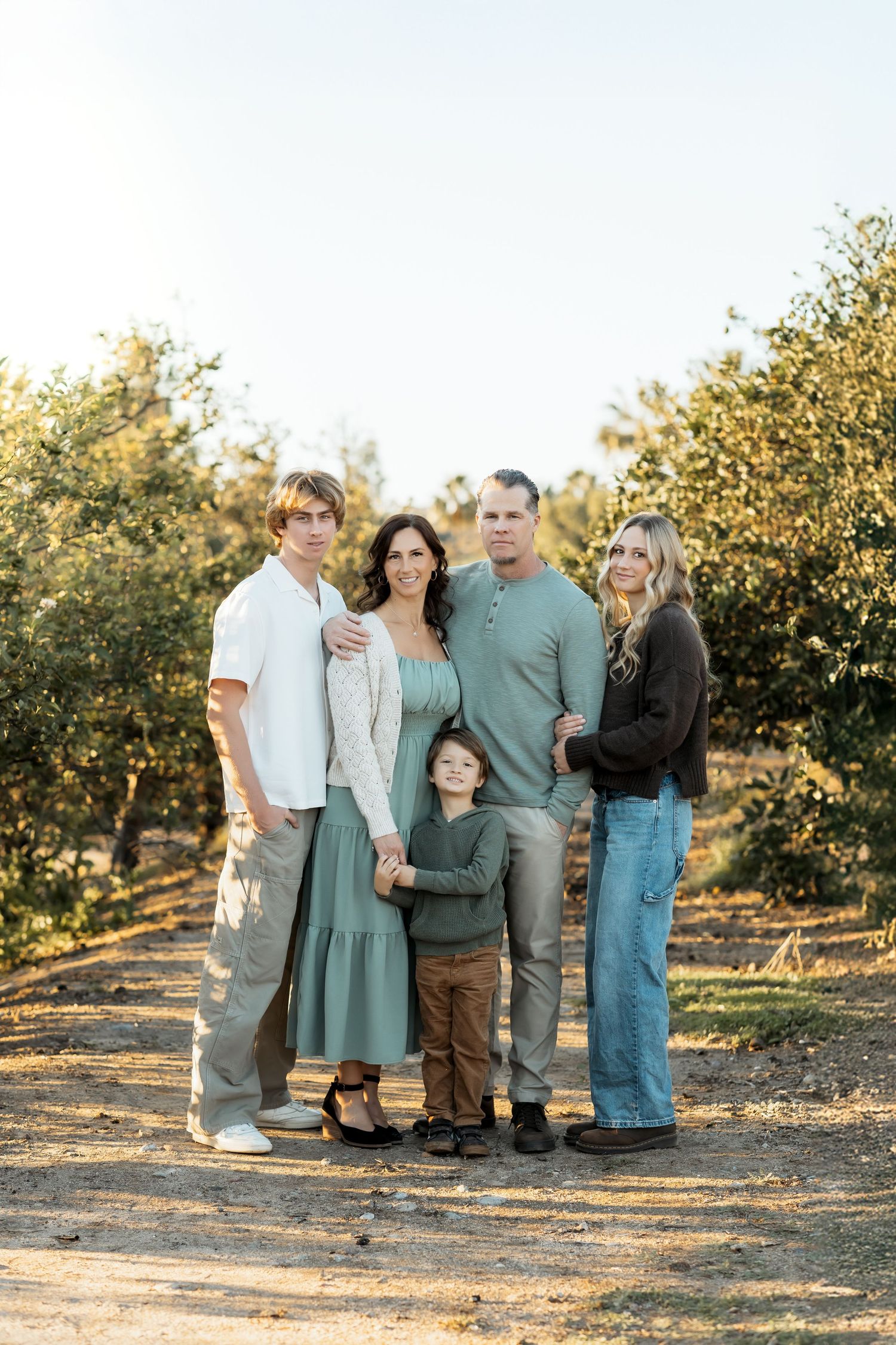 Family smiling at the camera during outdoor portrait session in Orange County