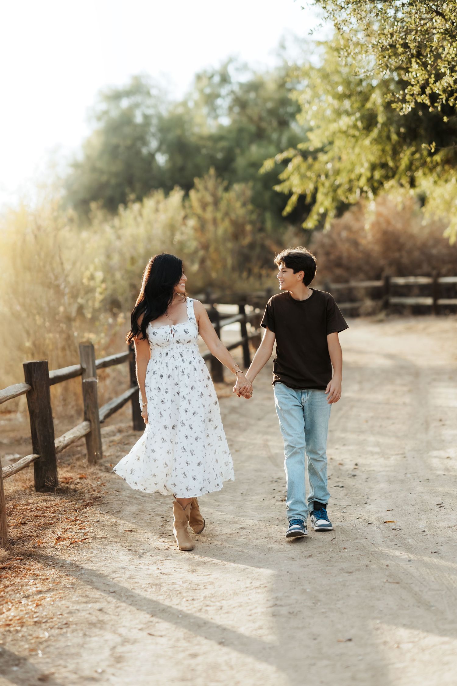Orange County family photographer walking outdoors with her young son, sharing a joyful moment and looking at each other.