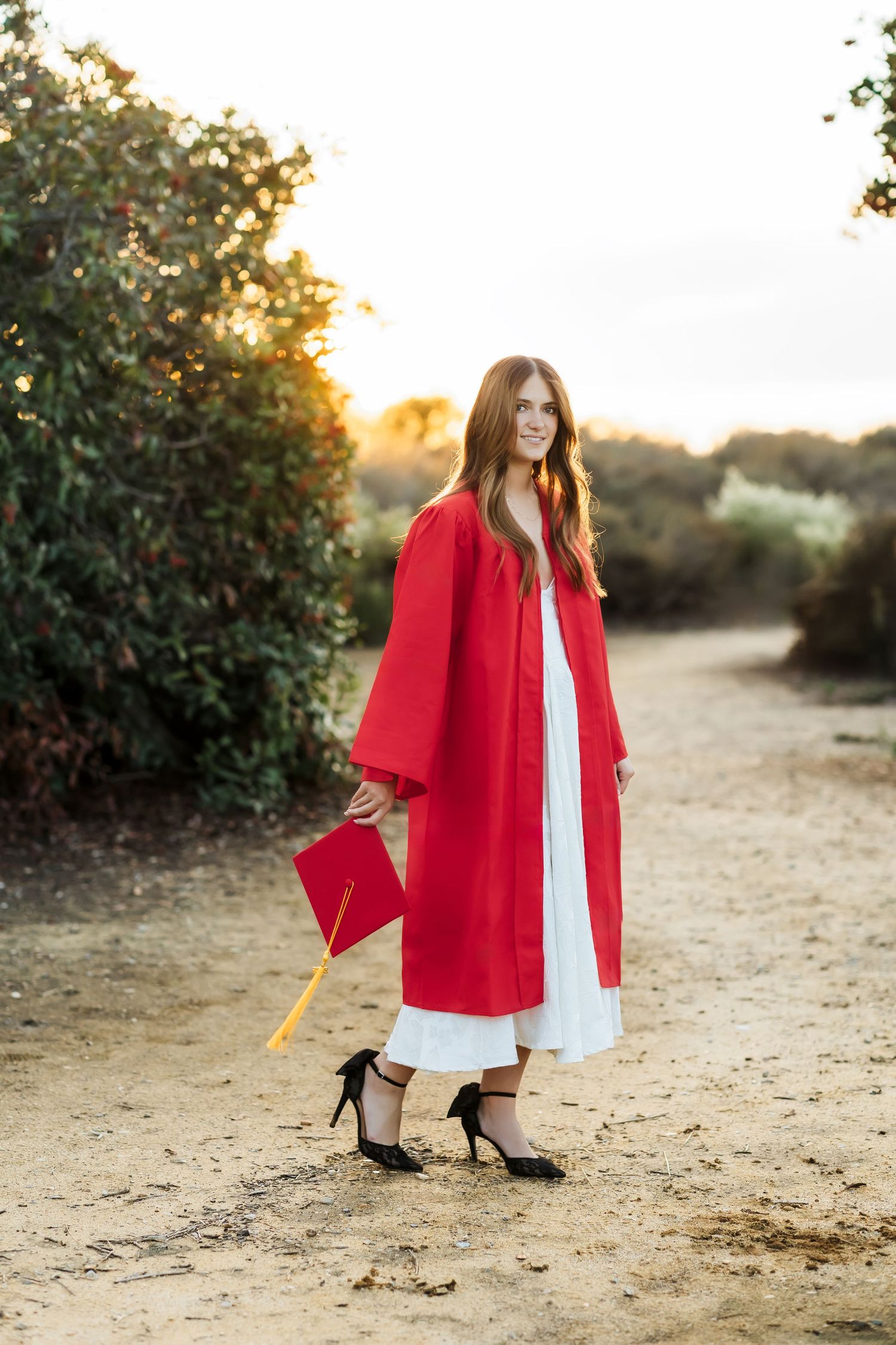 Fullerton grad session with cap and gown on a trail at sunset