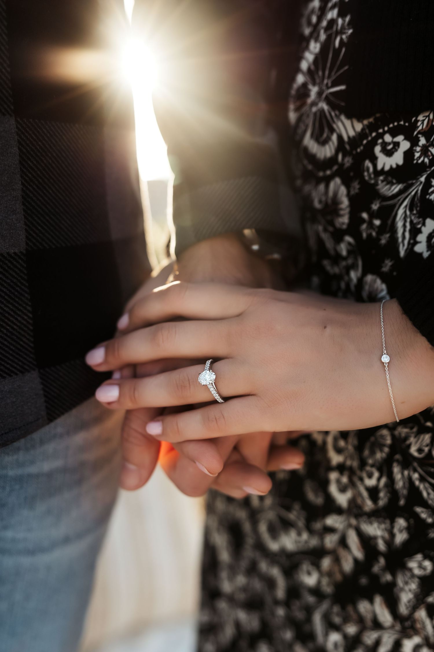 A newly engaged couple holding hands showing her ring at an engagement session at Newport Beach, CA
