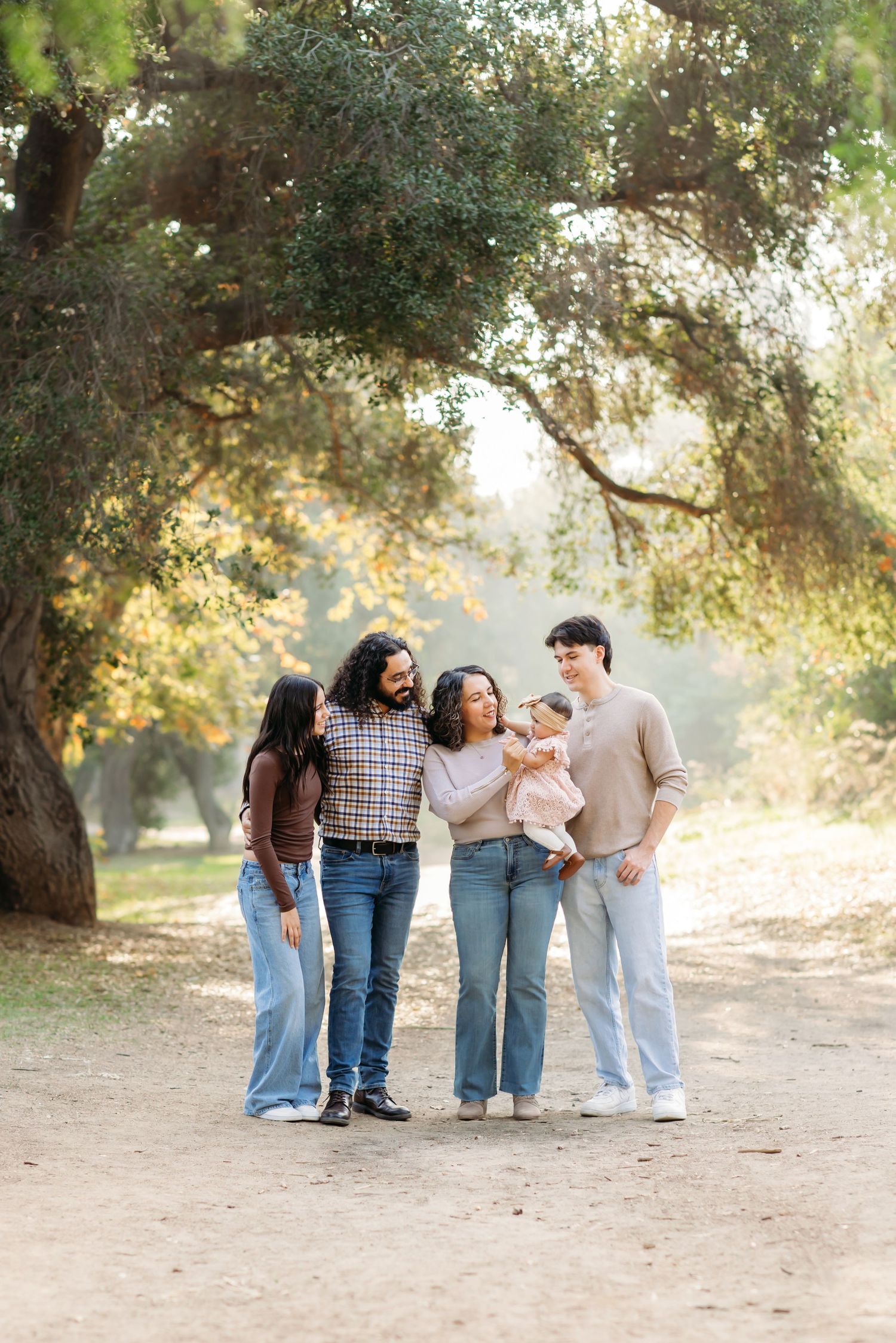 A family standing together admiring the newborn daughter during a natural light family portrait session in Fullerton, CA