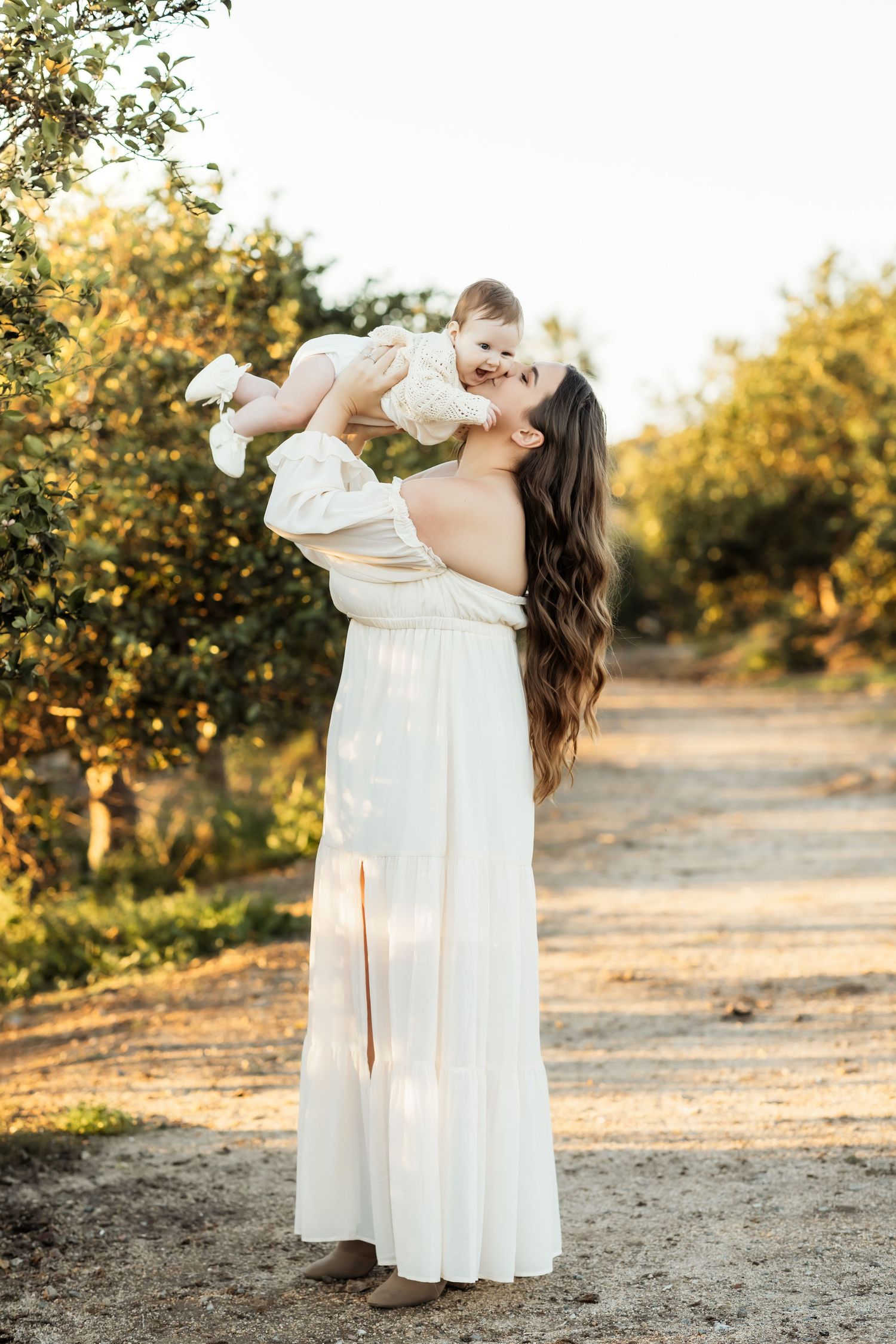 Mom holding her baby up while she smiles during a family photo session in Orange County