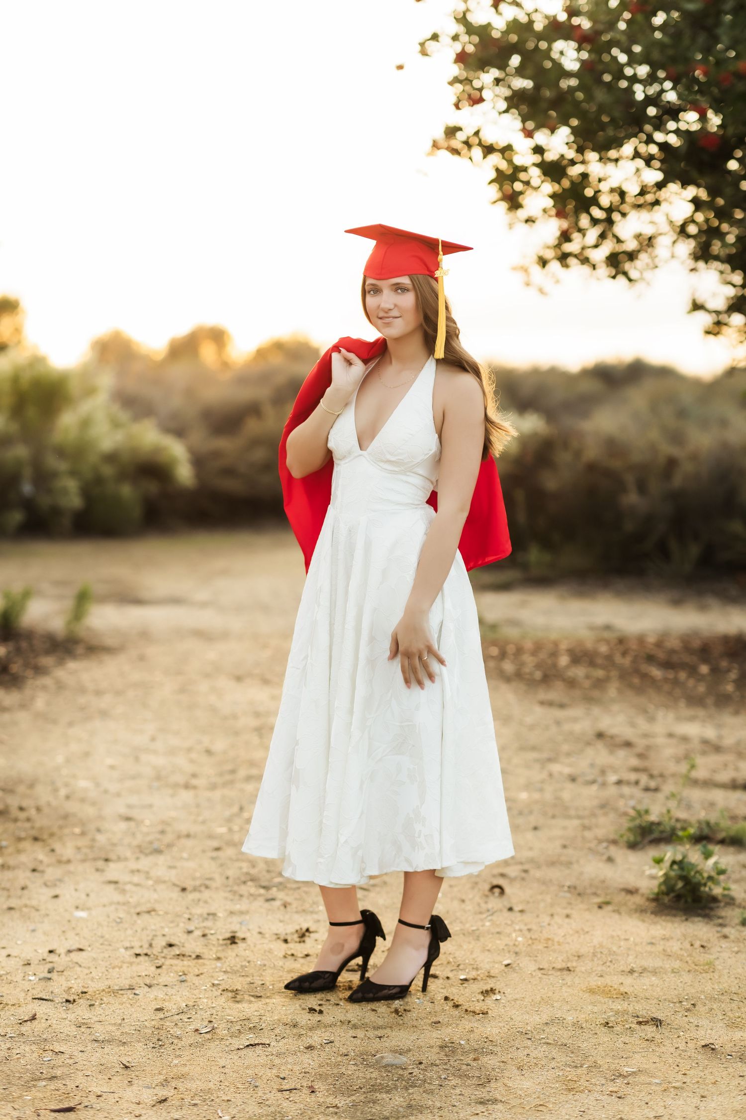 Senior grad photo of girl in white dress with cap and gown during a sunset photo session in Fullerton, CA