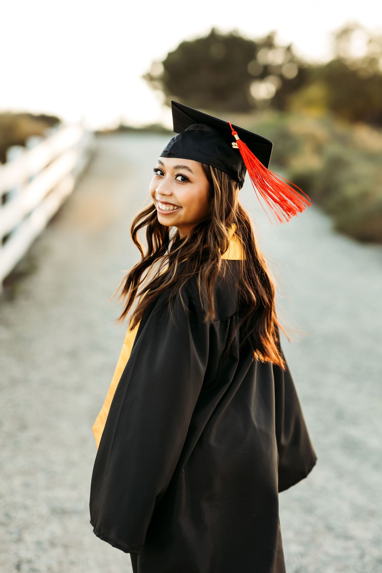 Confident grad portrait in natural light wearing  a cap and gown in Fullerton, CA.
