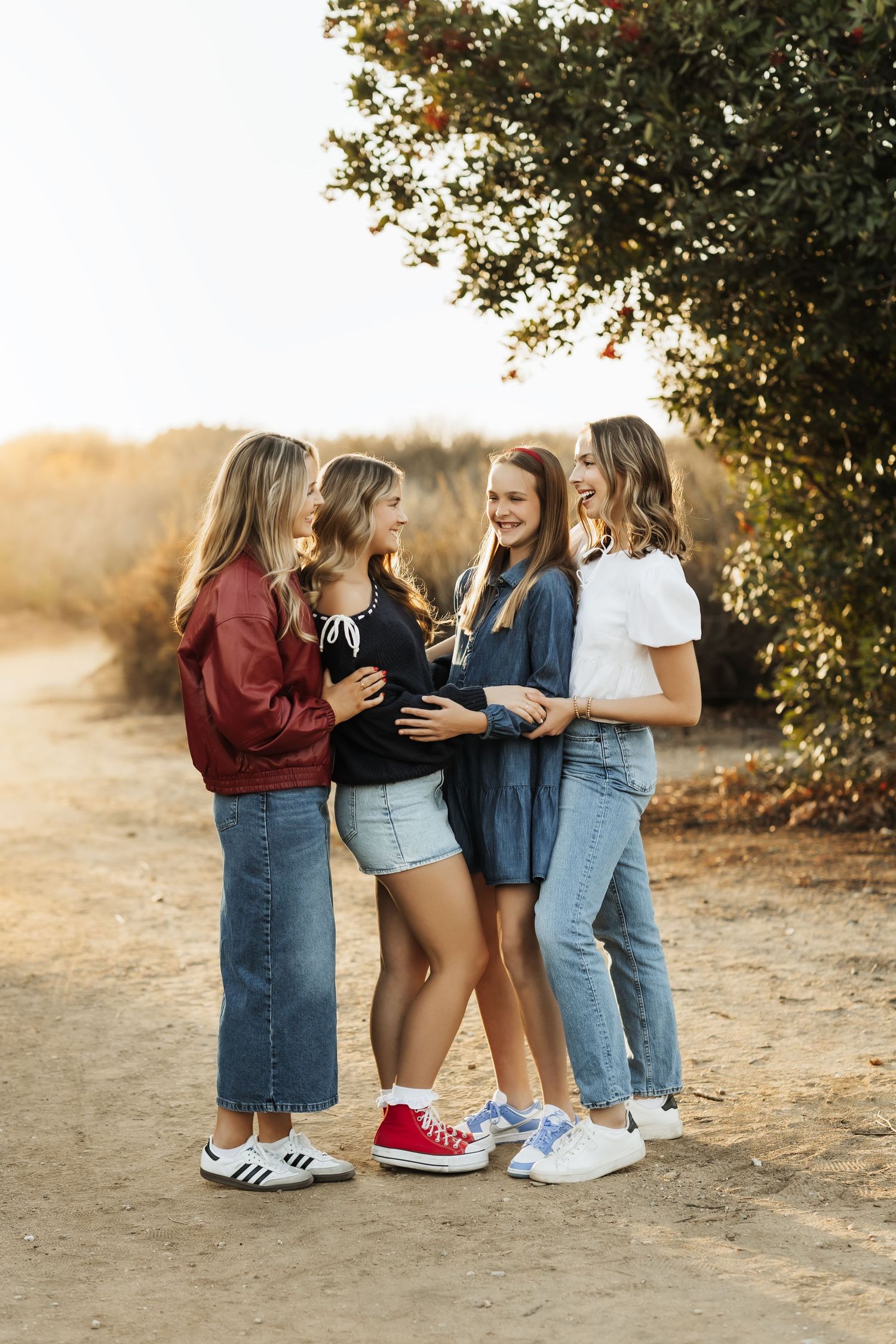 Sisters looking at each other and smiling during a family portrait session in Orange County at sunset