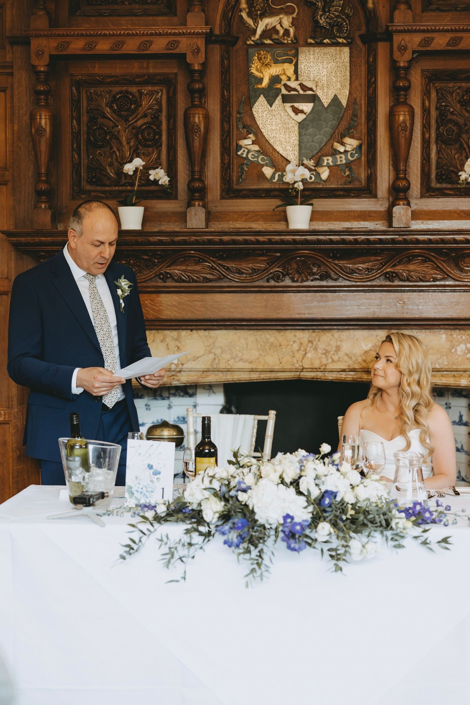 Wedding reception dining setup with blue and white flowers along an elegant table in a historic venue.