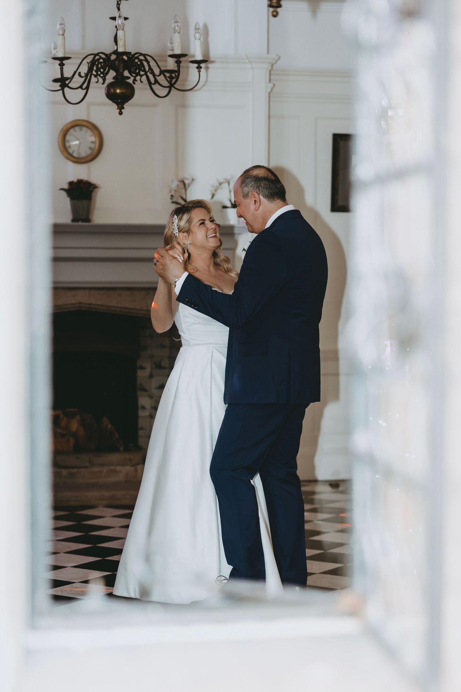 Romantic dance captured through white pillars in an elegant ballroom setting.