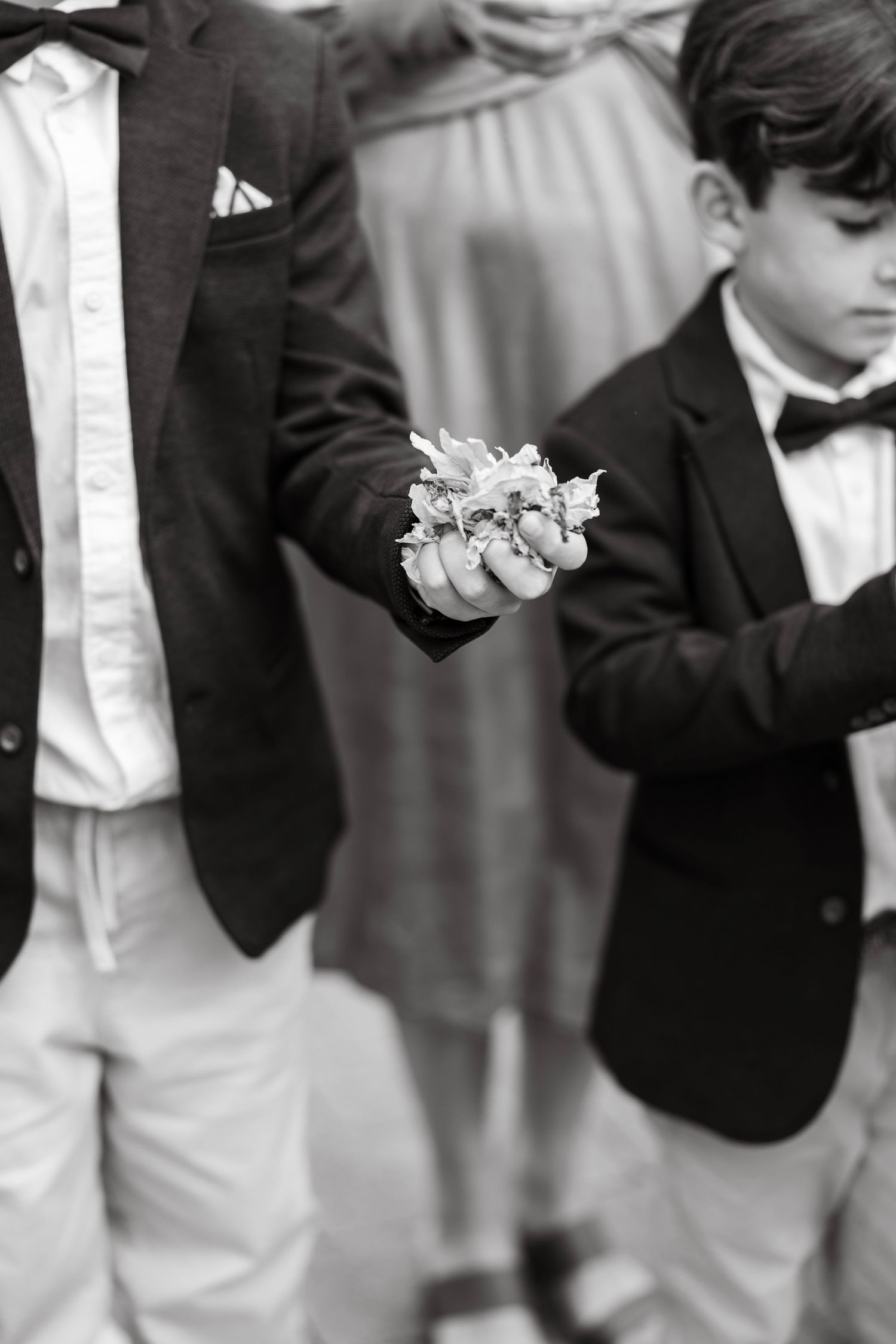 Young attendants in formal black and white attire at wedding ceremony.