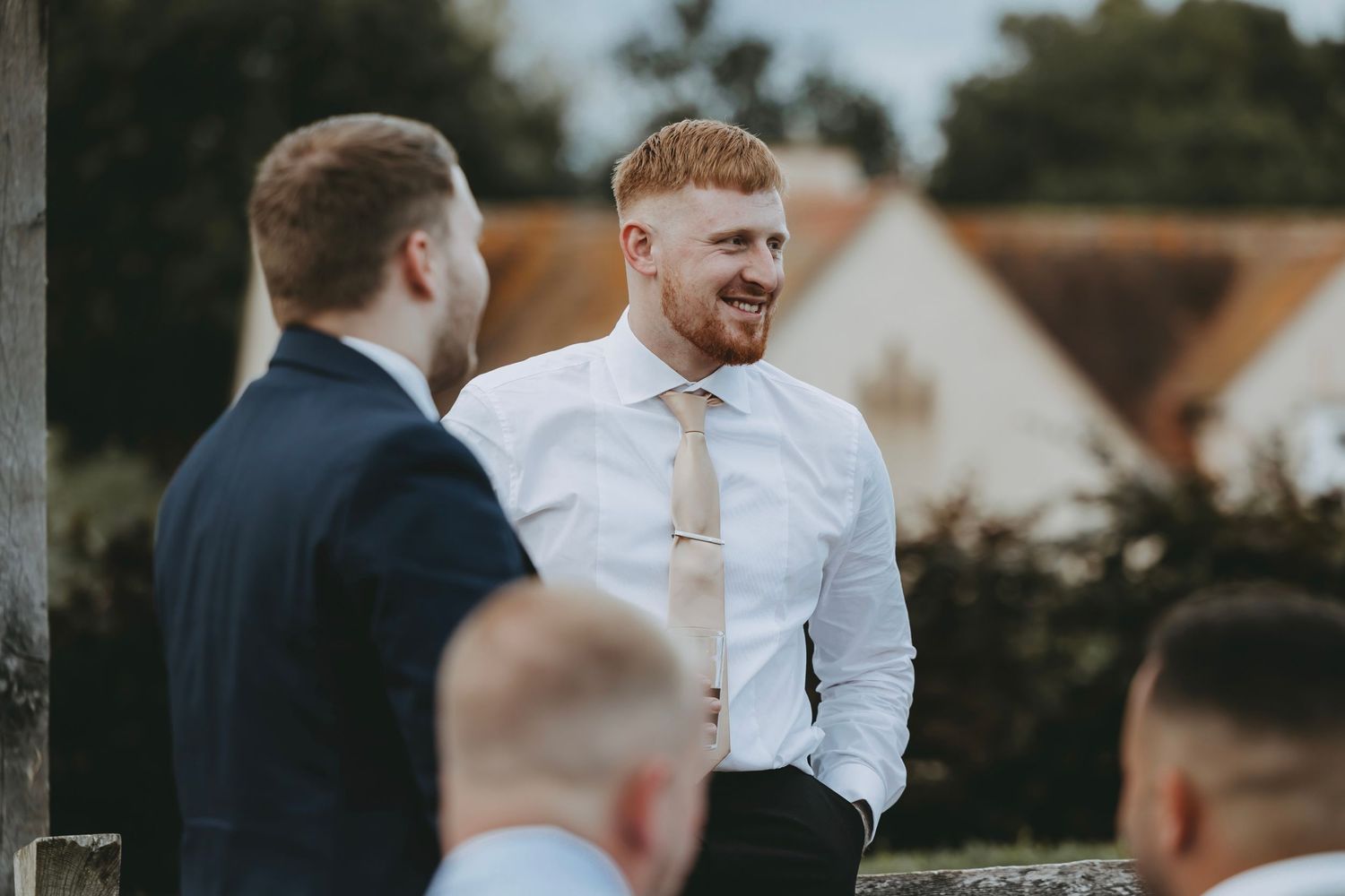 Guests in formal wear interact during an outdoor wedding event.