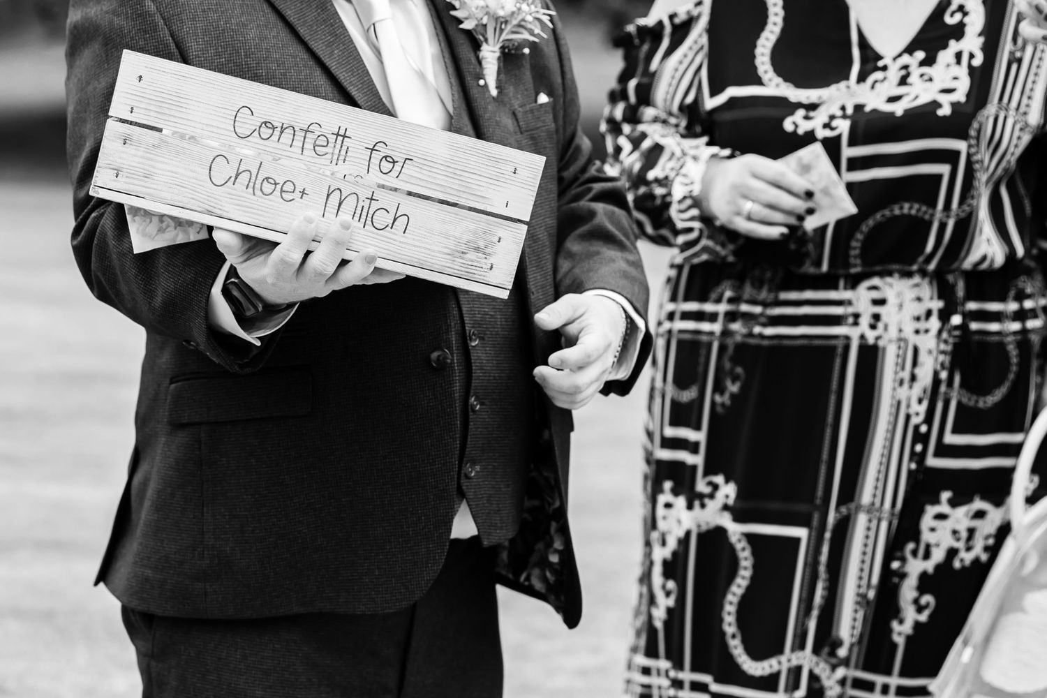 Black and white photo of wedding guests holding signs at an outdoor ceremony.