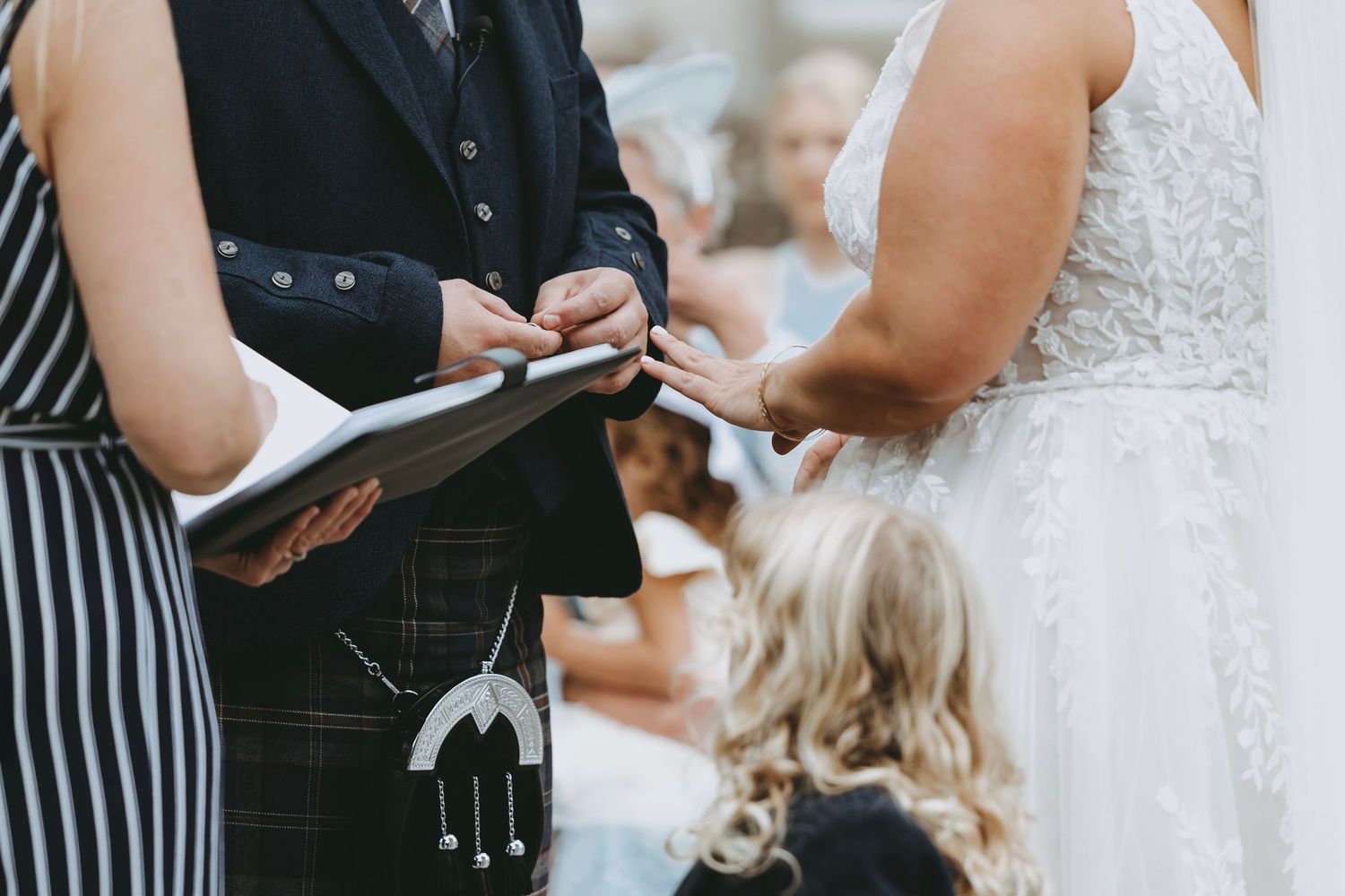 Intimate moments during wedding ceremony with bride in lace dress and guests in formal wear.