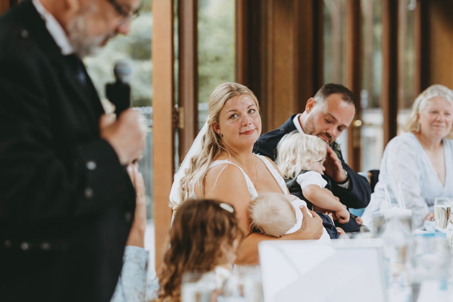 Candid moments of wedding guests during reception dinner in rustic venue.