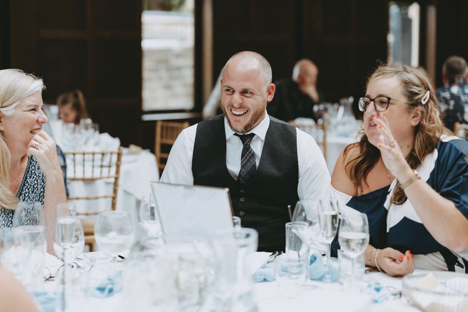 Wedding guests seated at long tables during an indoor reception celebration.