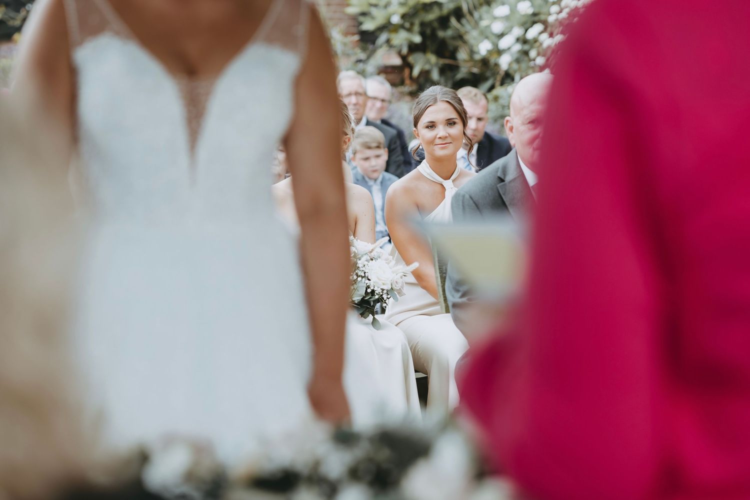 Candid moment captured during outdoor wedding ceremony with guests in background.