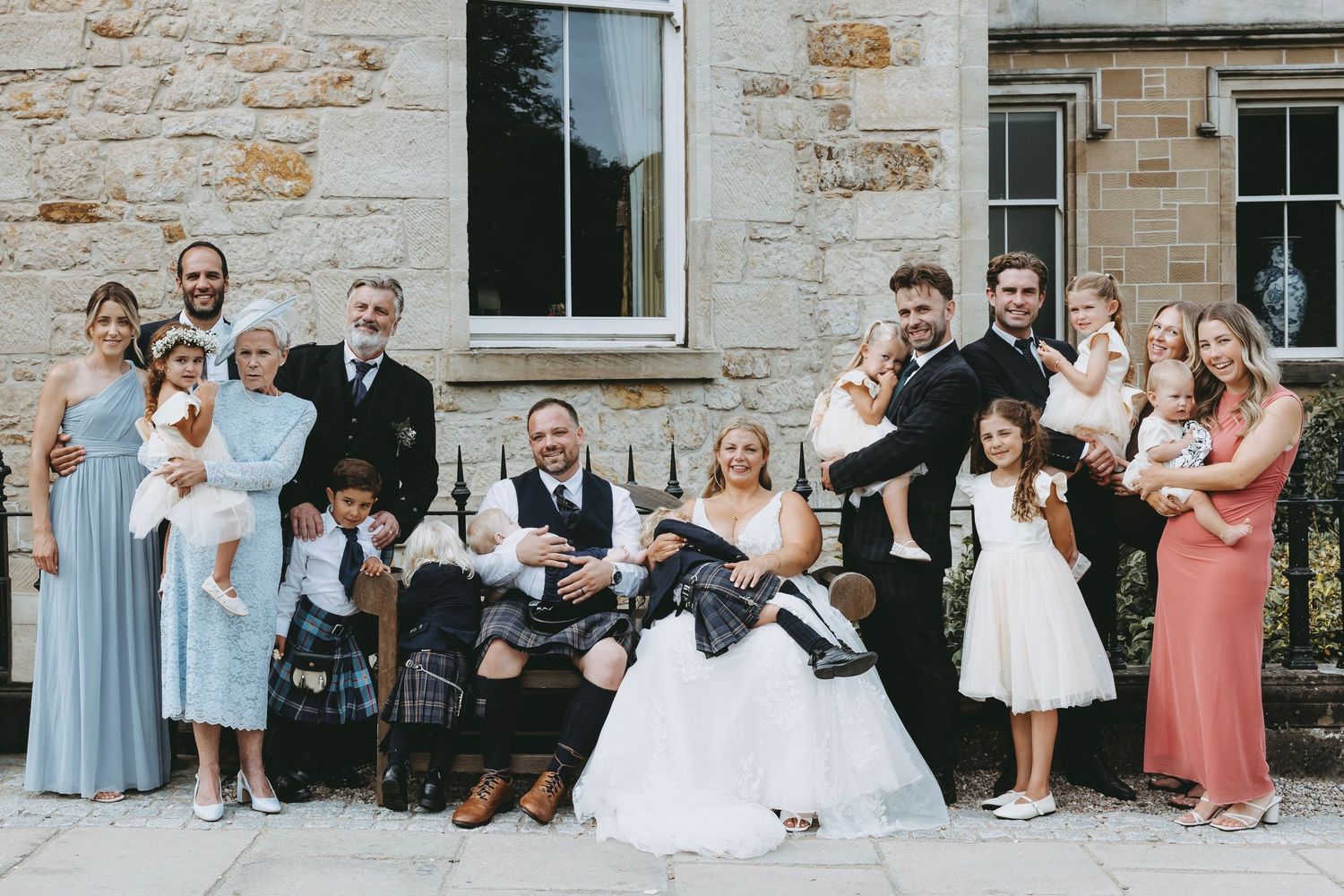 Wedding party poses together on stone steps for formal group photo.