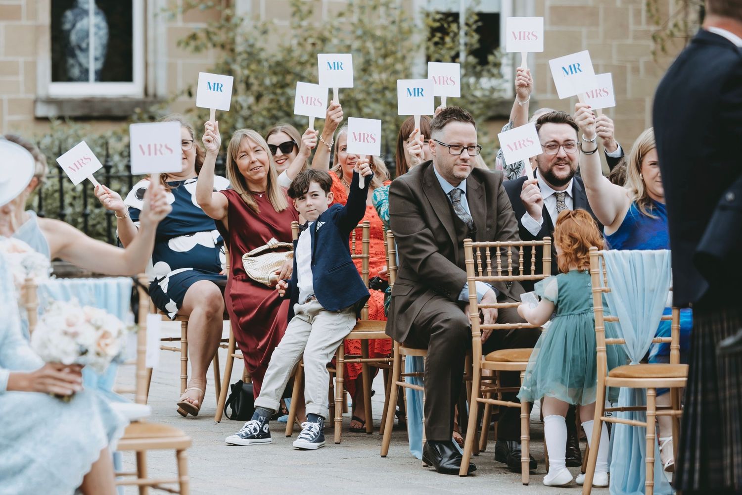 Wedding guests hold up signs during interactive reception game at stone venue.