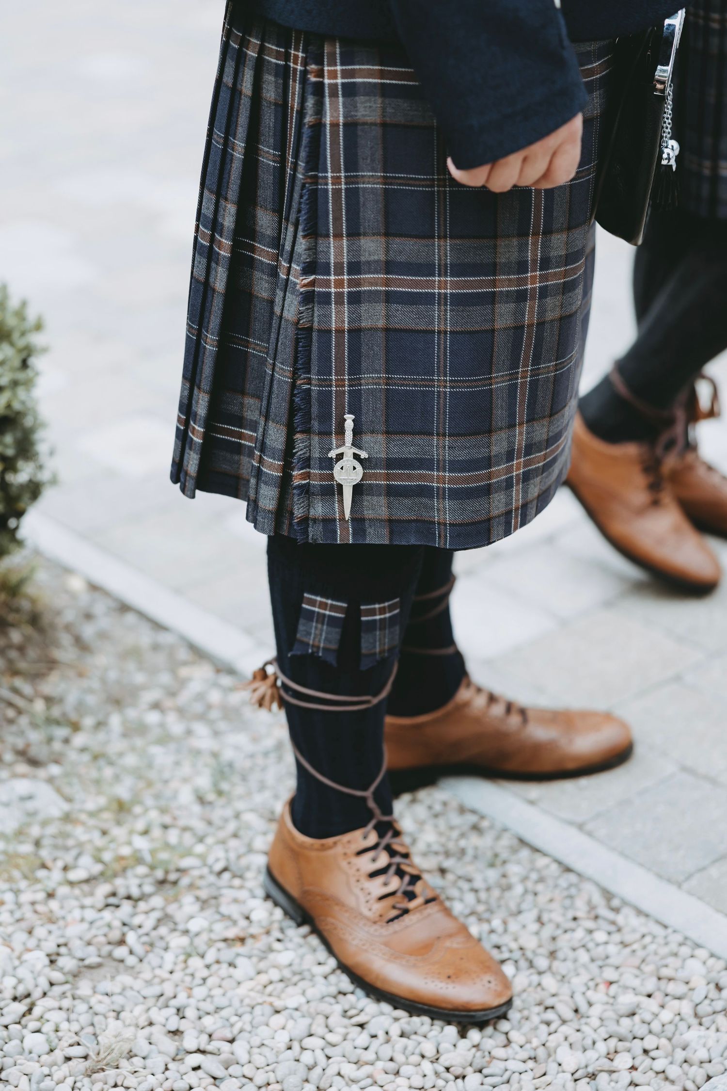 Detail shot of brown leather shoes and traditional Scottish kilts.