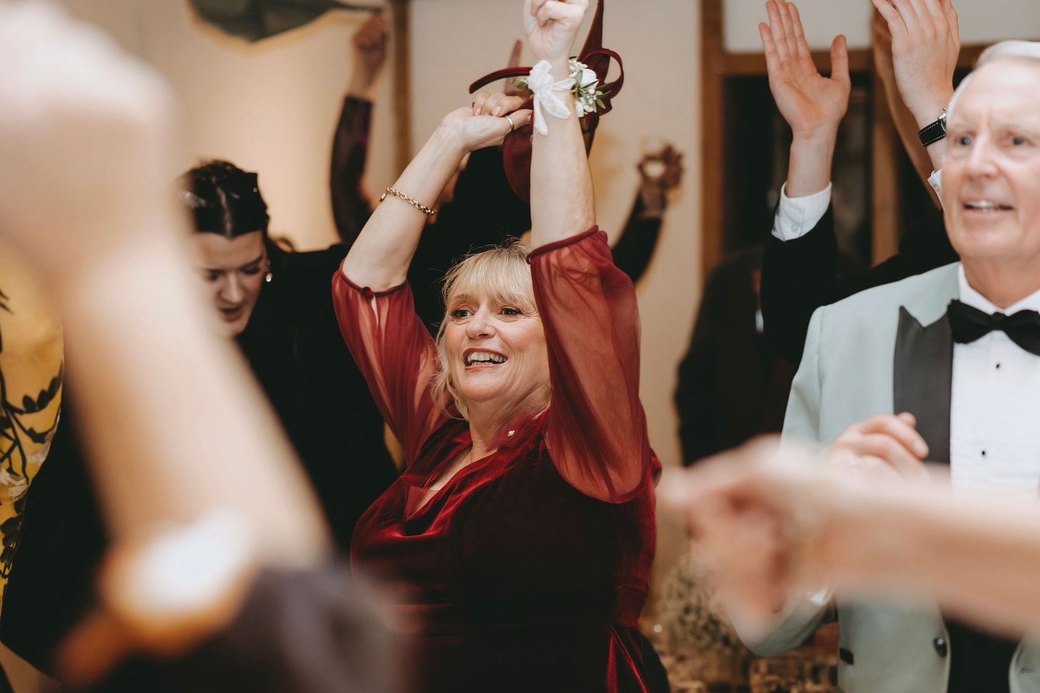 Wedding guests dancing and celebrating enthusiastically during reception party.