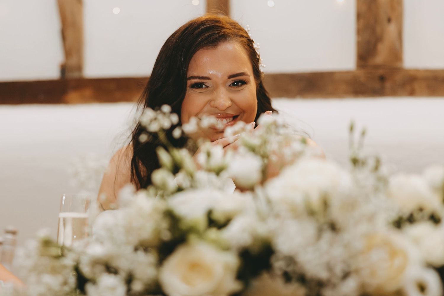Elegant white floral centerpieces with roses and greenery decorate wedding reception tables.