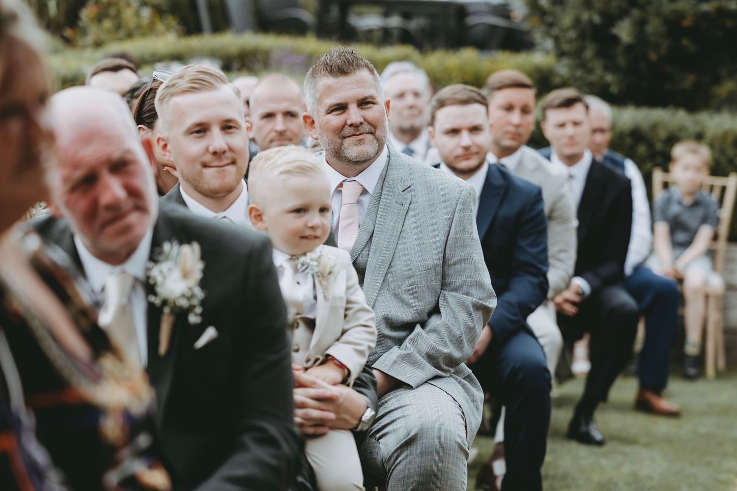 Joyful wedding celebration with guests smiling in an outdoor garden setting.