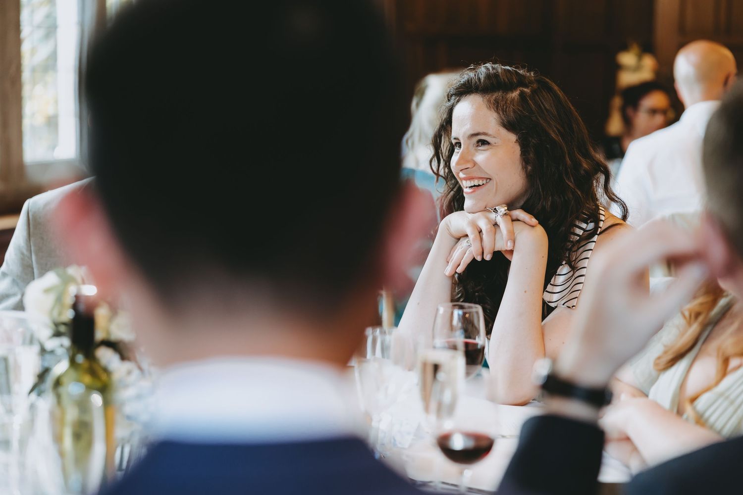 Wedding reception guests seated at long tables with wine glasses and formal place settings.