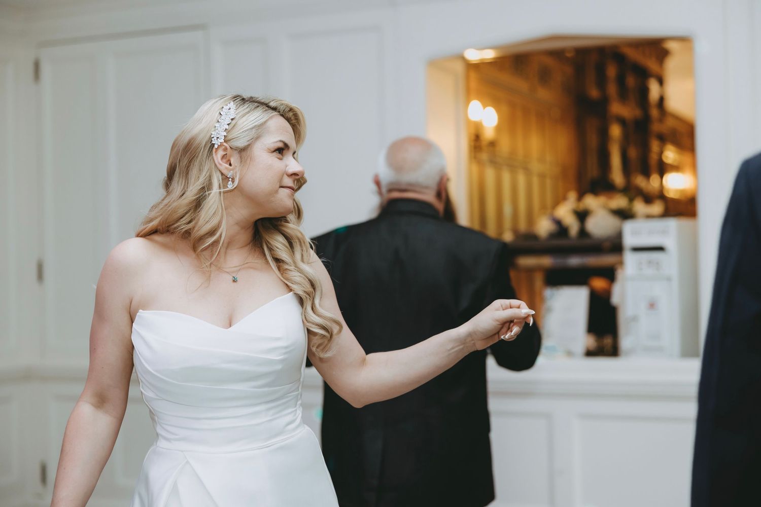 A bride in a white gown dances at a wedding reception in an elegant indoor venue.