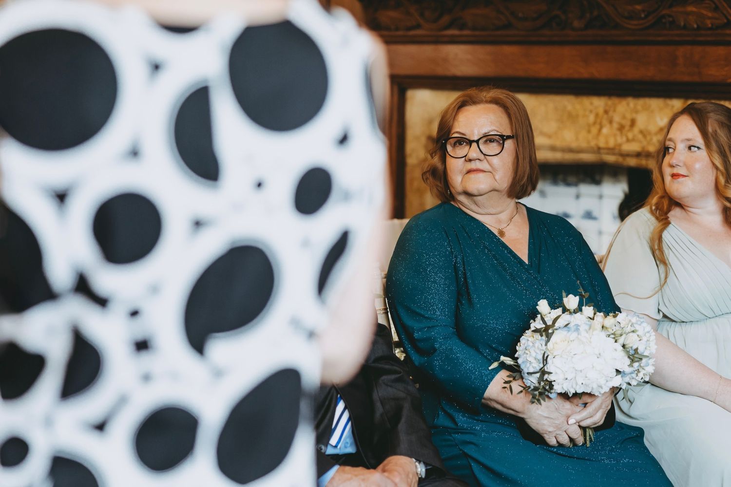 Elegant wood-paneled interior with wedding attendees and decorative circular patterns.