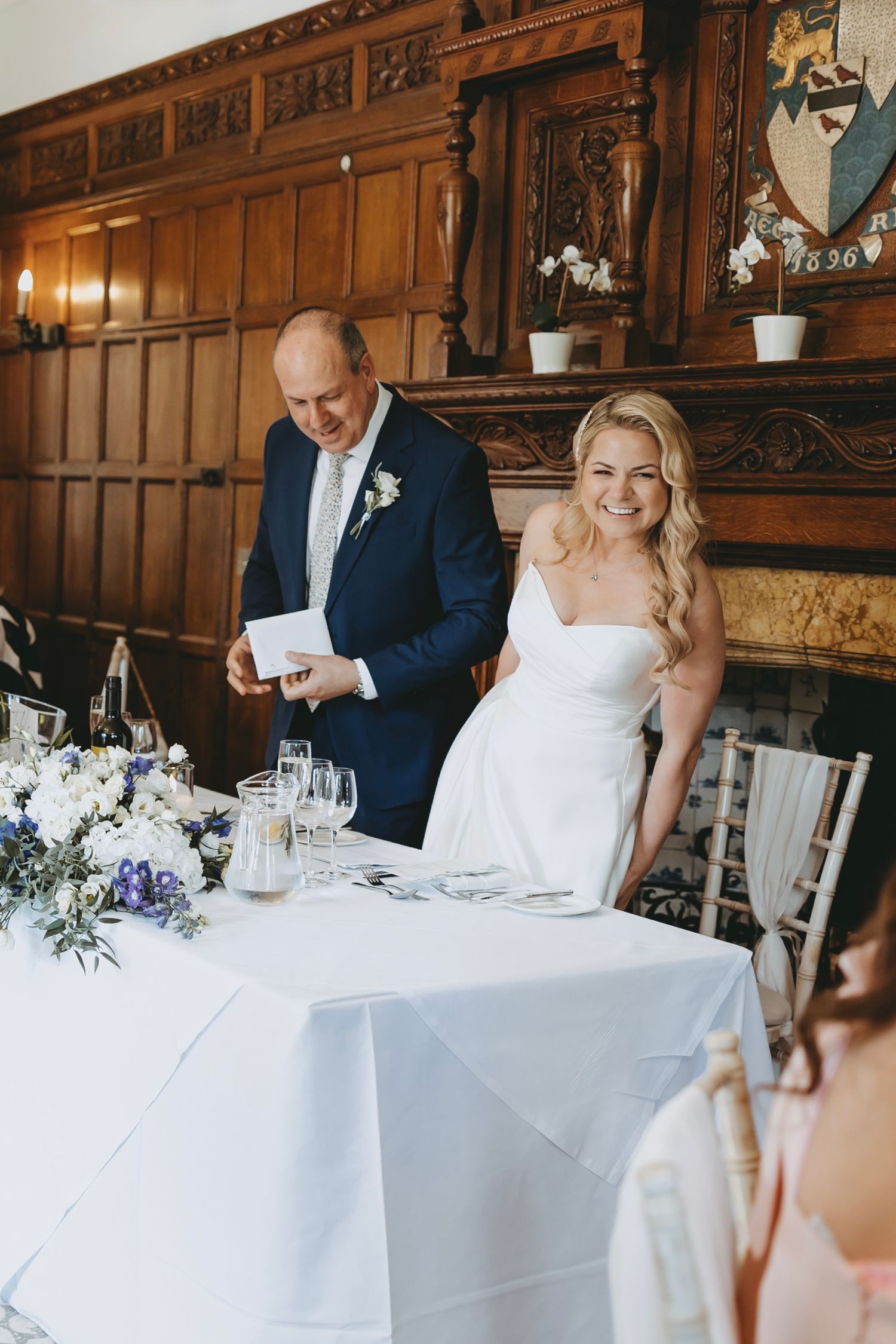 Wedding reception in a wood-paneled dining room with elegant table settings and floral centerpieces.