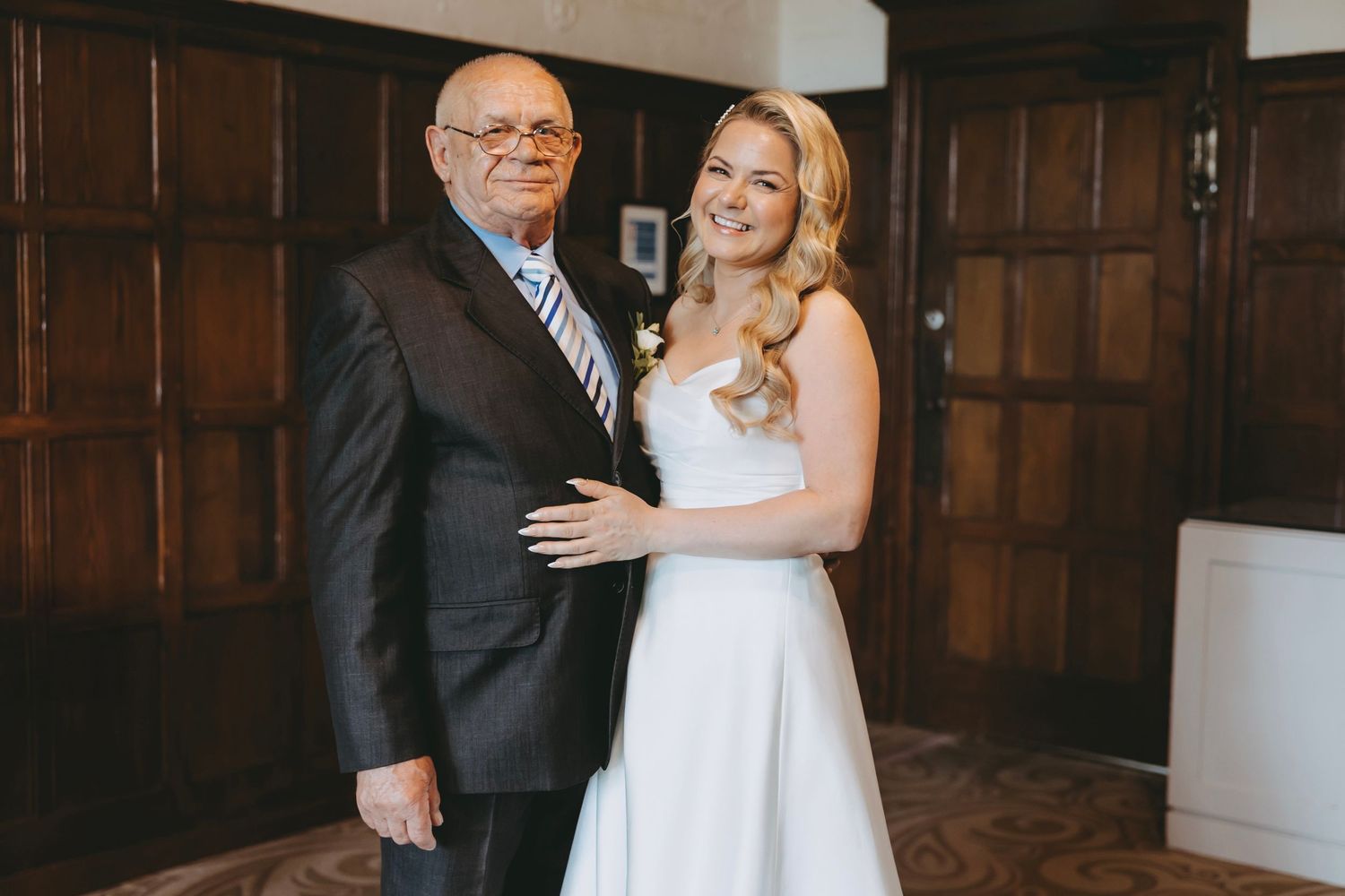 A tender moment captured between a bride and senior gentleman in formal wear.