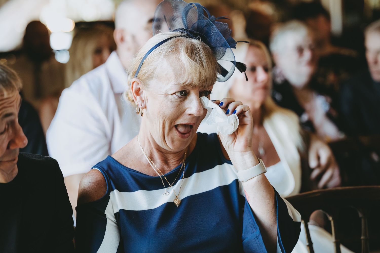 Wedding guests react emotionally during ceremony in rustic venue.