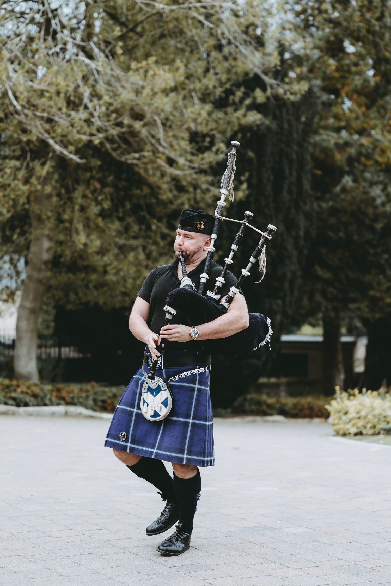 Bagpiper in traditional Scottish kilt playing pipes during outdoor performance.