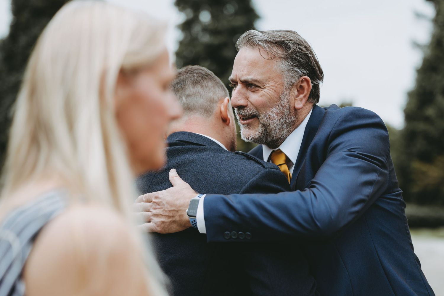Candid moments of guests interacting during a formal outdoor celebration.