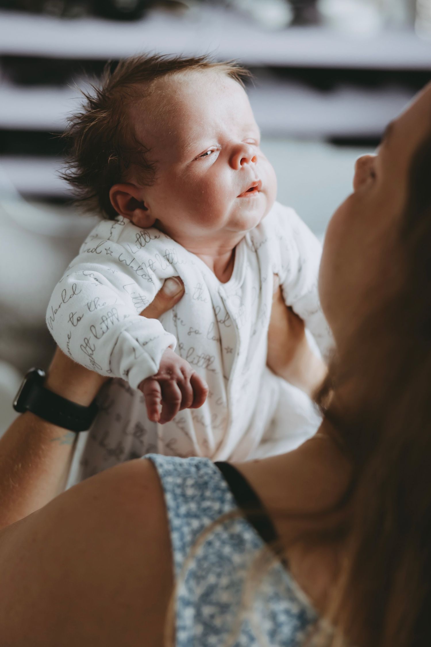 A series of intimate moments showing a baby in white clothing against a dark floral background.