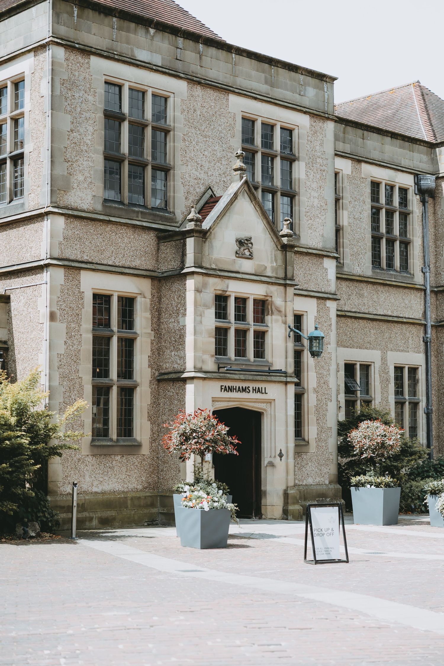 Elegant stone facade of Parkland Hall entrance with ornate windows and decorative planters flanking the doorway at Fanham Hall, Ware, Herts