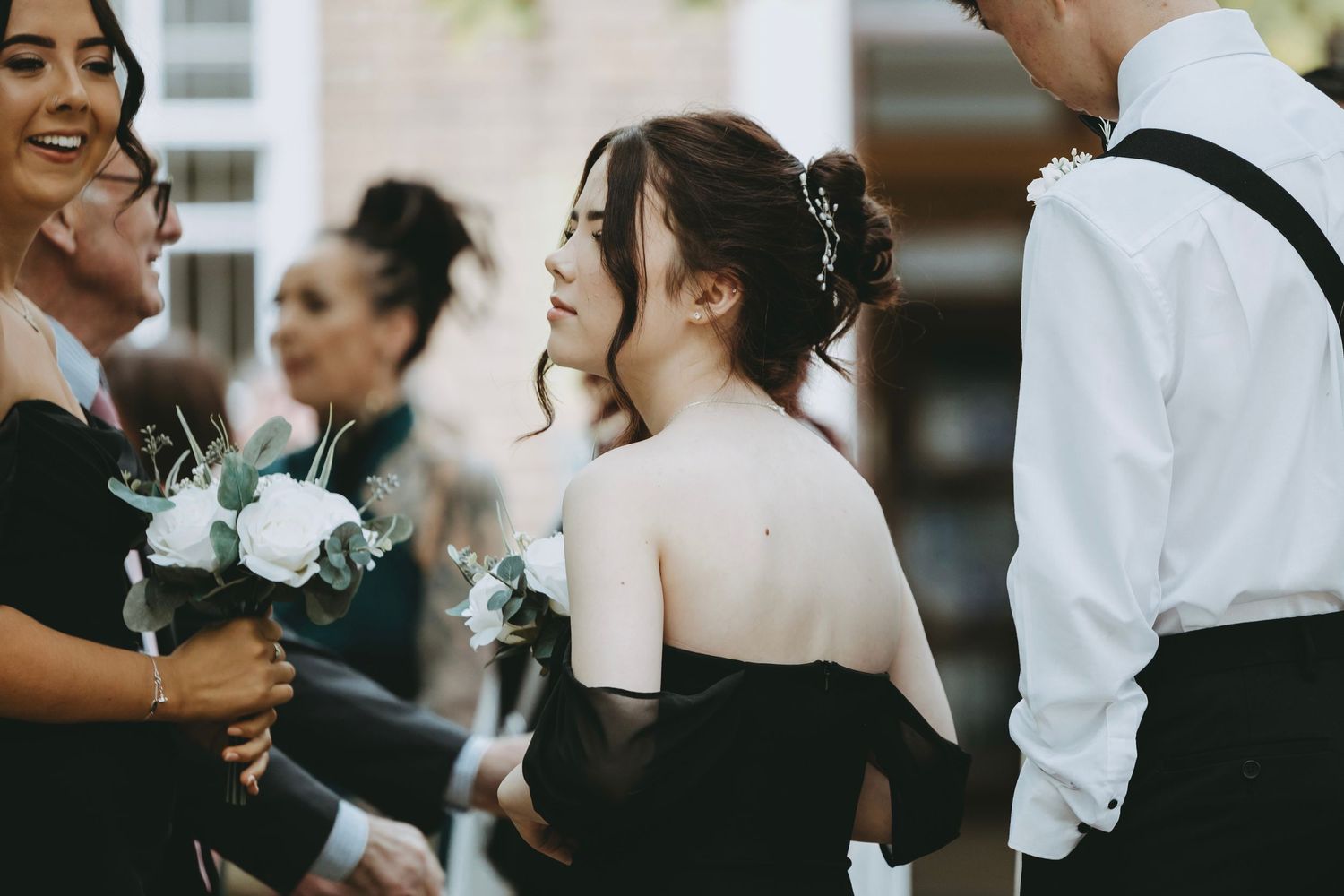 Wedding party members share casual moments during outdoor photo session.