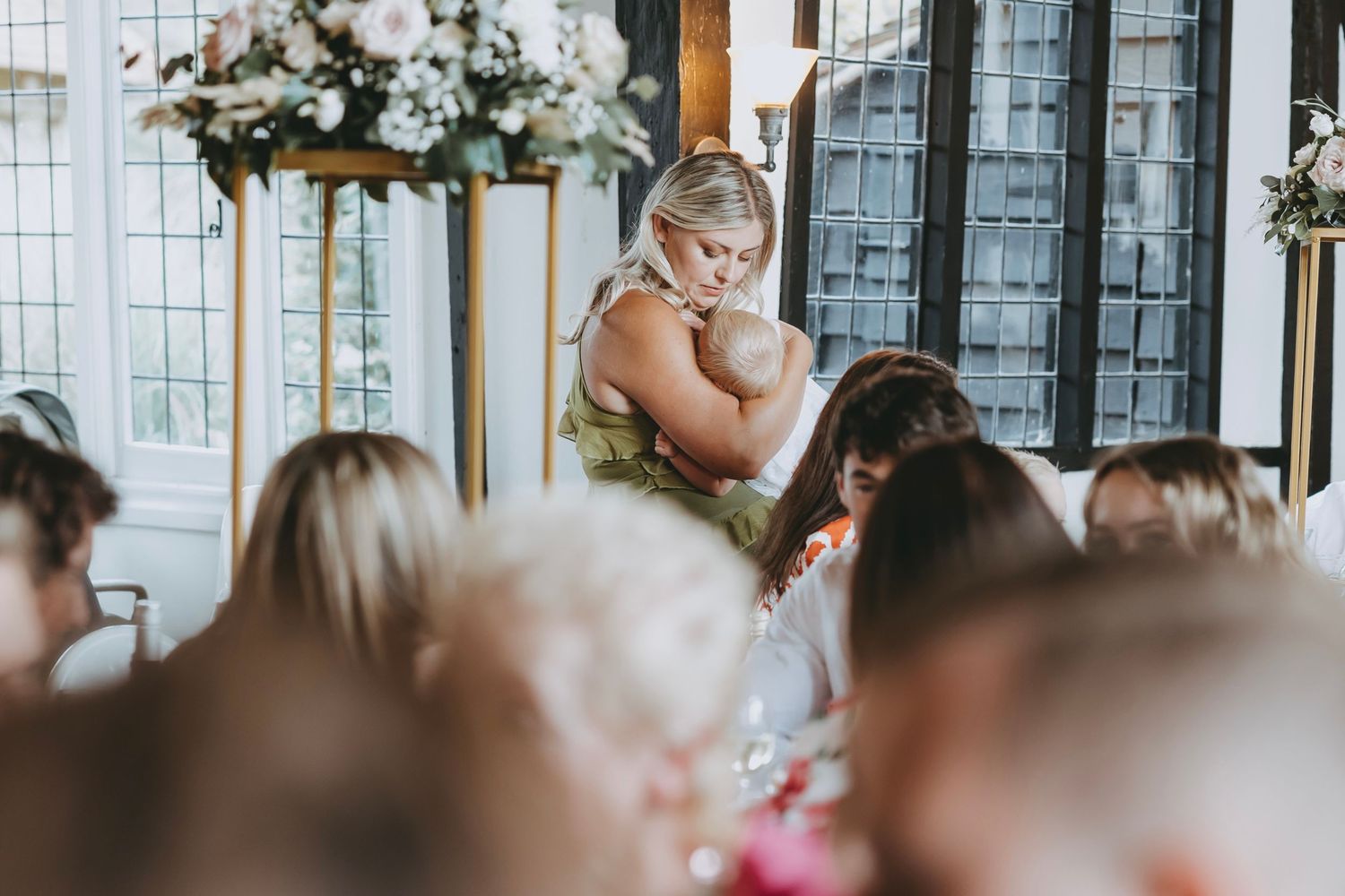 Elegant wedding reception venue with white floral centerpieces and natural lighting through windows.