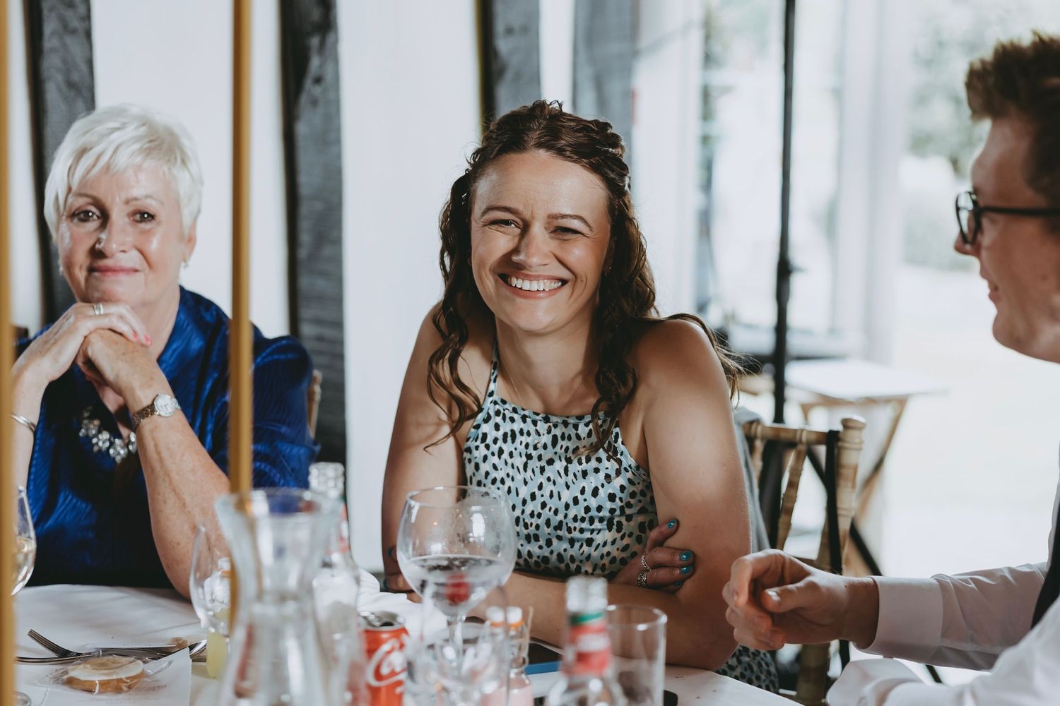 Wedding reception guests enjoying conversation at tables decorated with floral arrangements.