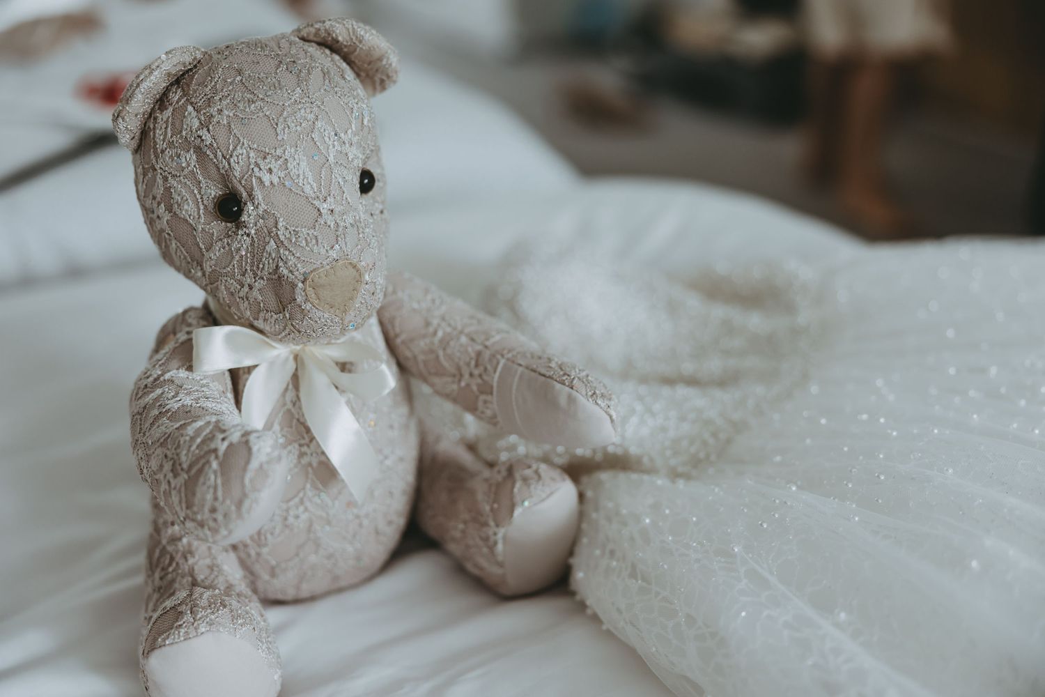 Plush teddy bear decorations sitting on white bridal fabric.