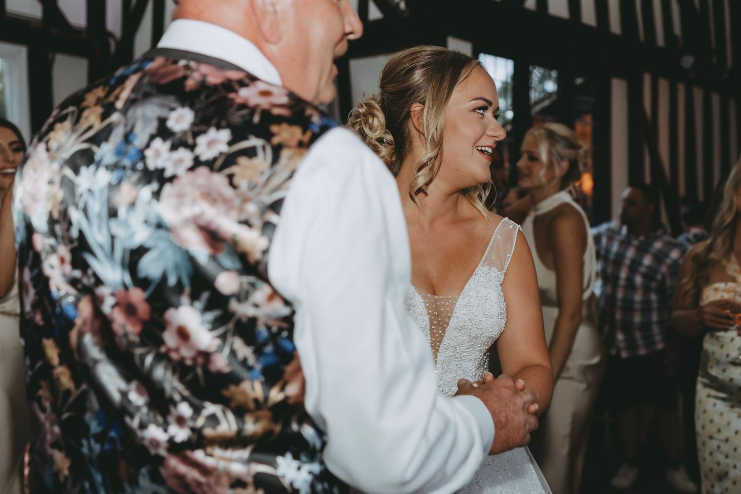 Wedding reception guests dancing energetically in a rustic venue with exposed wooden beams.