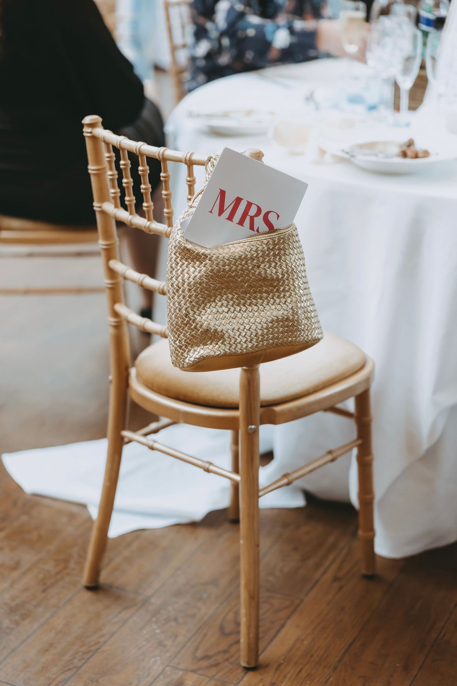 Wooden chiavari chairs with woven details and white cushions at wedding reception.