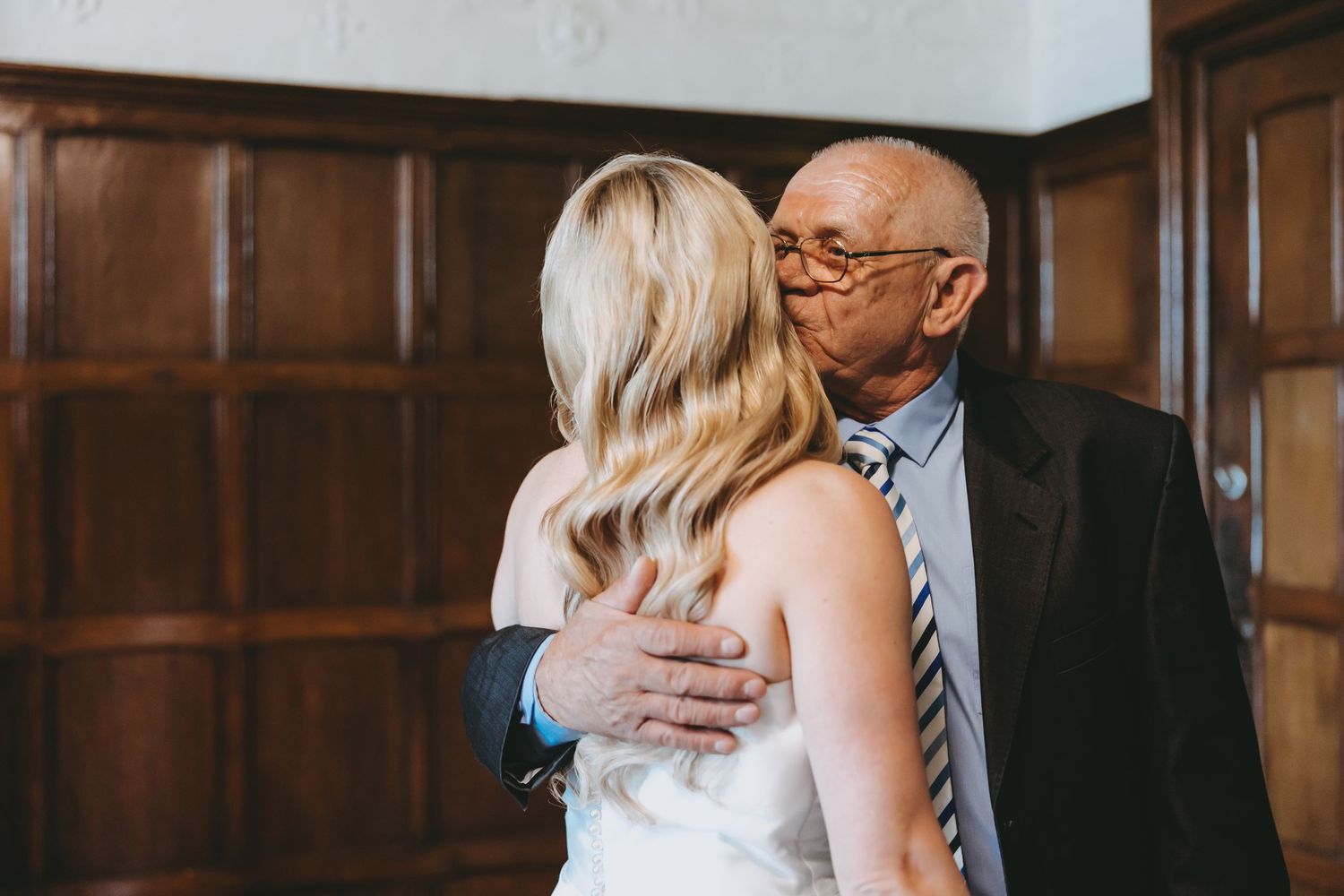 A heartfelt embrace during a wedding ceremony in a traditional venue setting.