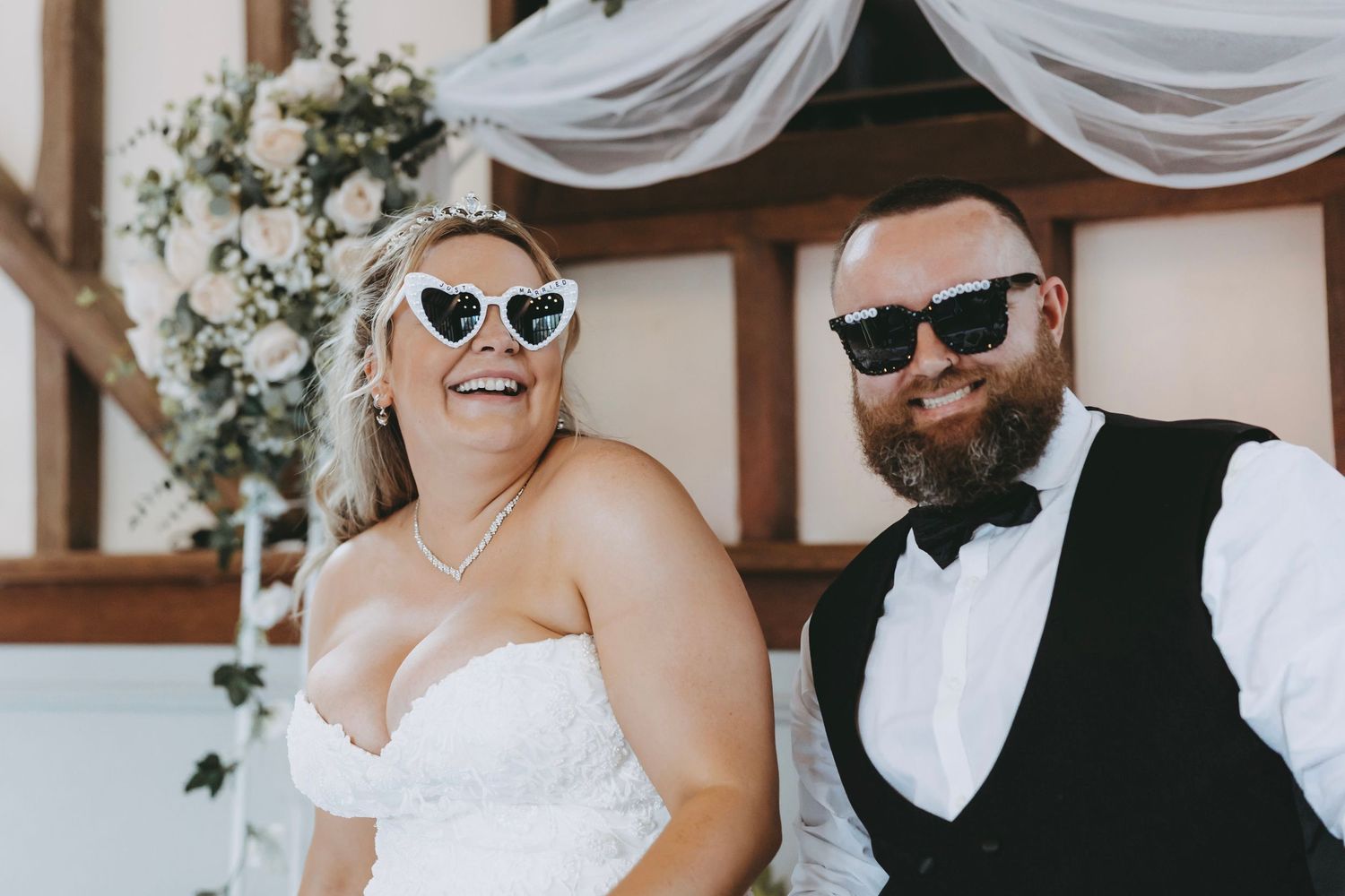 Wedding party members wearing sunglasses and formal attire share a candid moment.
