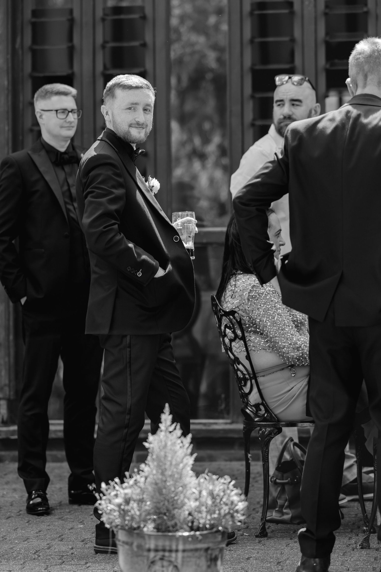 Black and white photo of wedding guests gathered outdoors in formal attire.