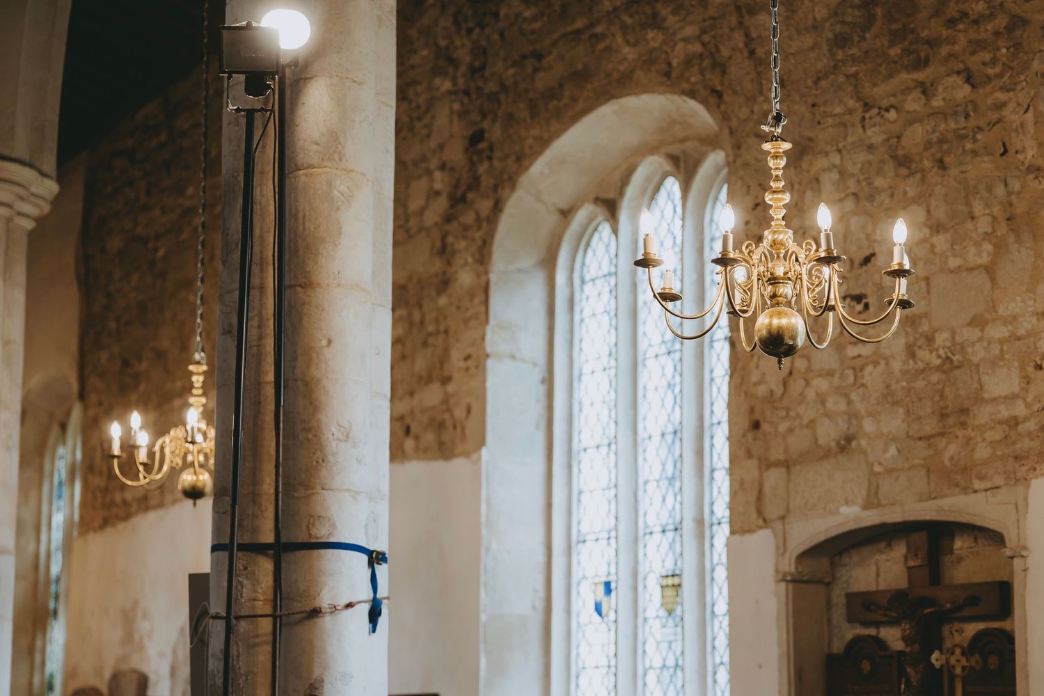 Historic stone church interior featuring dramatic archways and hanging chandeliers.
